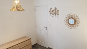 A hallway with a wooden bench, a white door, a wall-mounted mirror, and decorative leaf and circular wall art. - Small stone house in the heart of Périgord Noir (Salignac-Eyvigues)
