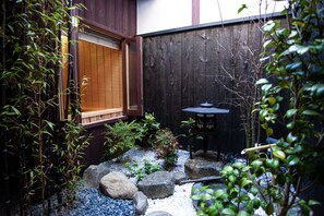 A traditional Japanese garden with a wooden window, a small table, and various plants. - Yamagata Kyomachi Hatago Gojo Nishitoin (Kyoto)