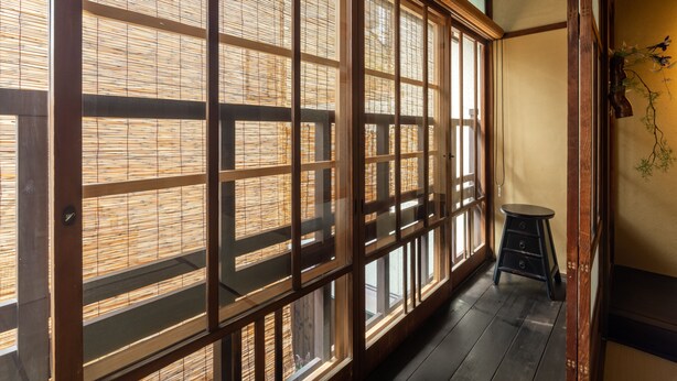 Una habitación japonesa tradicional con suelo de tatami, puertas correderas shoji y un pequeño taburete.