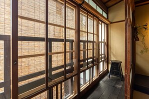 A traditional Japanese room with tatami flooring, sliding shoji doors, and a small stool.