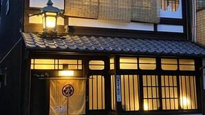 Un edificio japonés tradicional con tejado de tejas, un farol y un cartel con caracteres japoneses.