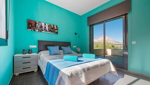 Una camera da letto con un letto grande, un comodino, un quadro e vista su una montagna.