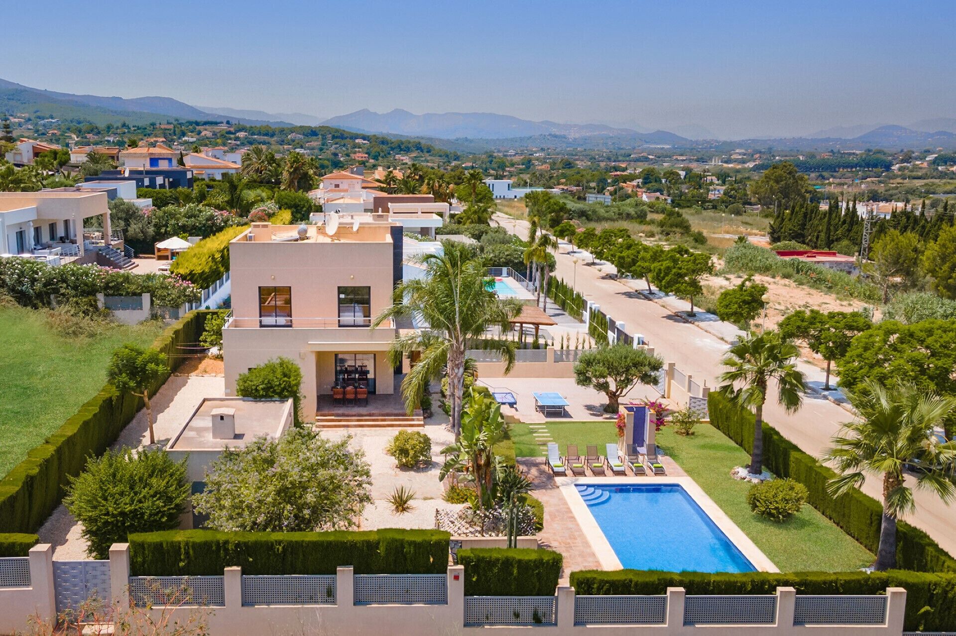 A modern villa with a swimming pool, surrounded by well-maintained gardens and palm trees.