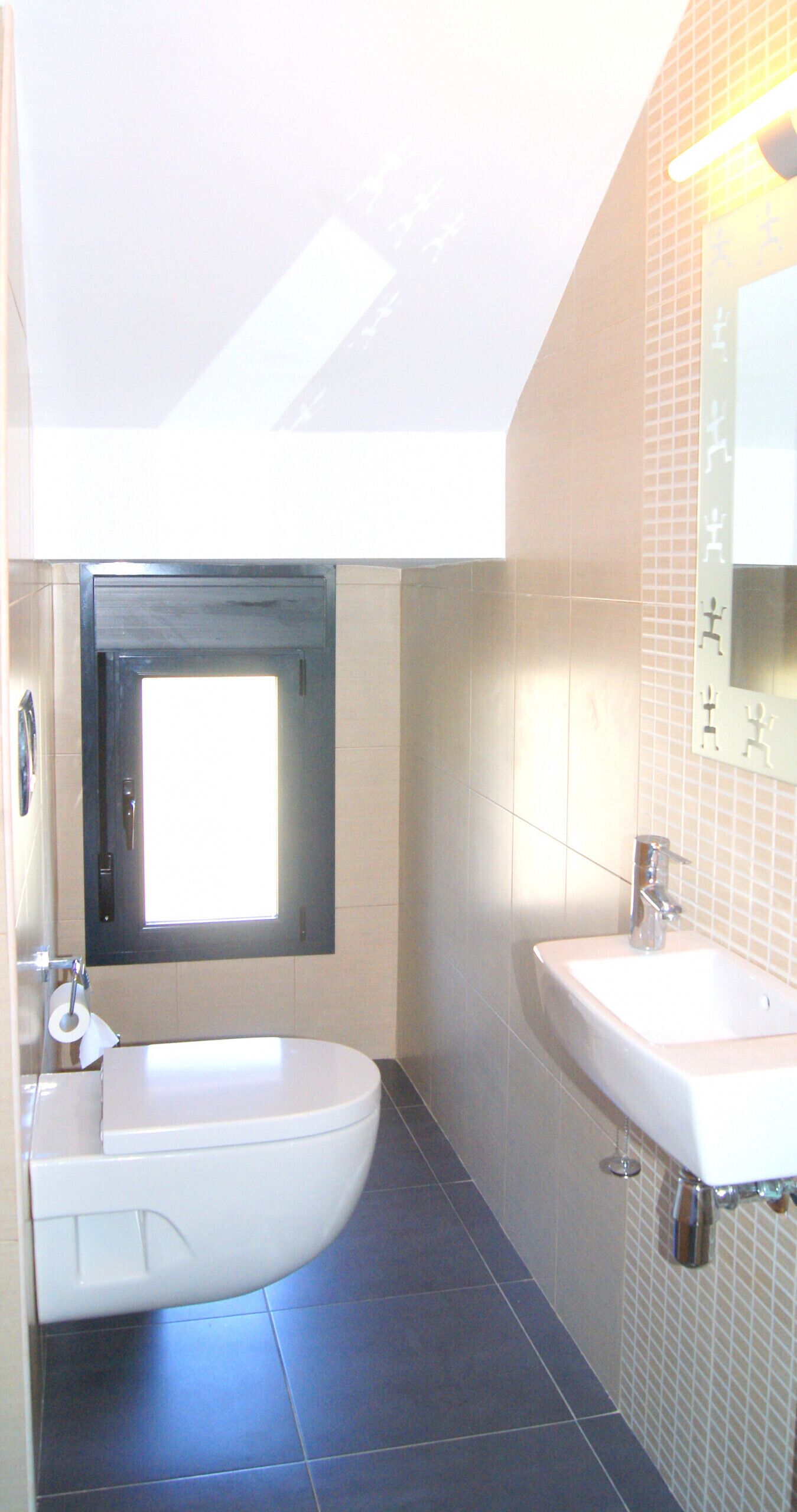 Un baño moderno con inodoro, lavamanos y ventana sobre el inodoro.