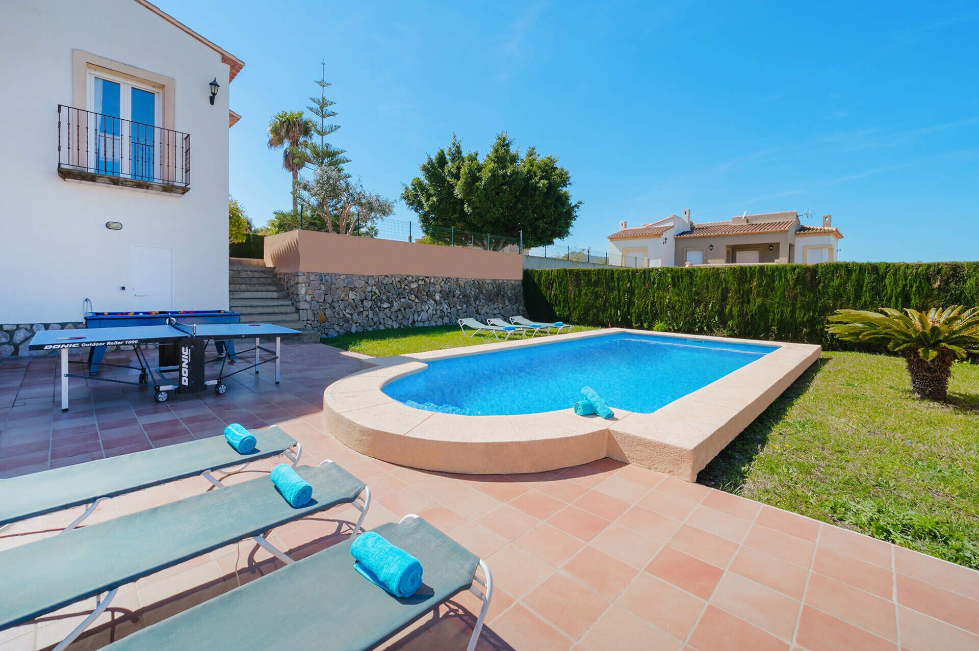 Una piscina con sillas de descanso, una mesa y un muro de piedra.