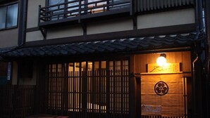 Un bâtiment traditionnel japonais, avec une entrée en bois, une lanterne au-dessus de la porte et une enseigne.