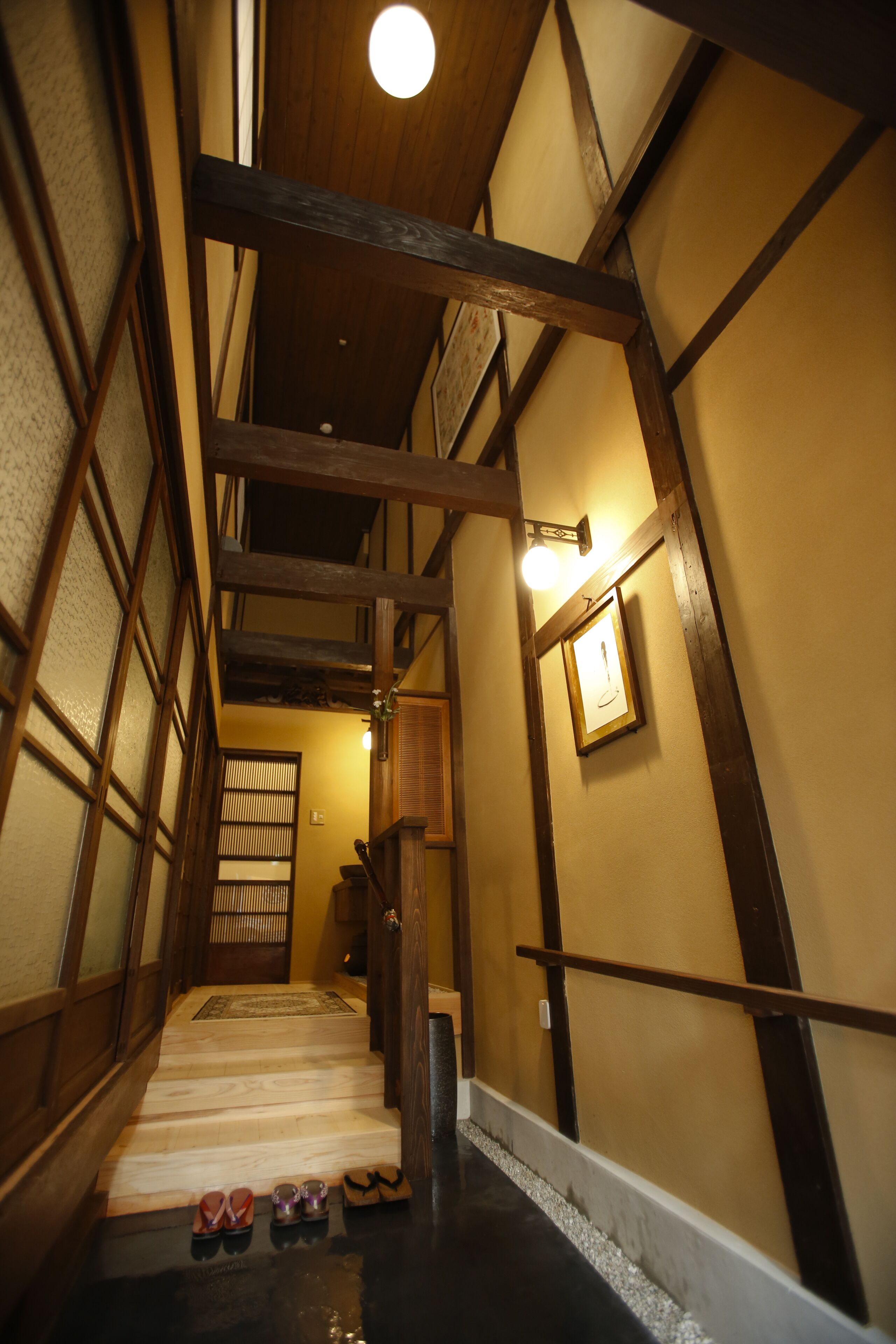 A traditional wooden staircase with a polished floor leading to a room with tatami mats.