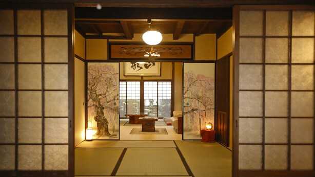 Une pièce de style japonais traditionnel, avec un sol recouvert de tatamis, une table basse et des décorations aux motifs de fleurs de cerisier.