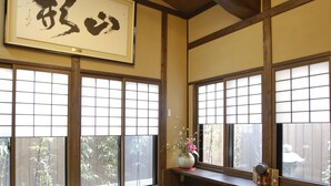 Une pièce de style japonais traditionnel, avec un sol recouvert de tatamis, une petite table en bois et des paravents en papier de riz (shoji).