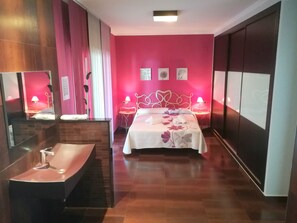 Relax in a stylish space with a large bed, modern vanity, and flat-screen TV.