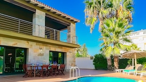 A pool area with a dining setup and a two-story building with balconies. - 0646 Villa Amanda Beach (Denia)
