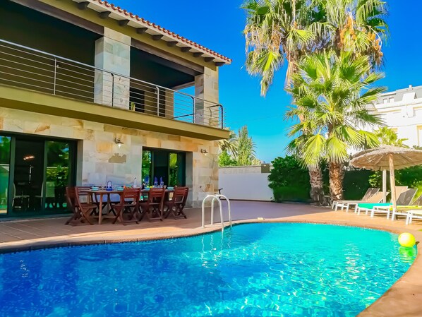 A pool area with a dining setup and a two-story building with balconies.