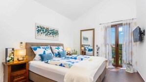 Een slaapkamer met een bed, nachtkastjes, een televisie en een raam met gordijnen.