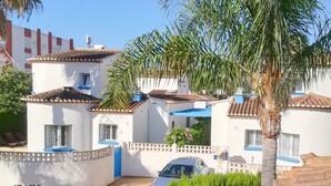Zona residencial con edificios blancos, detalles en azul y una palmera.