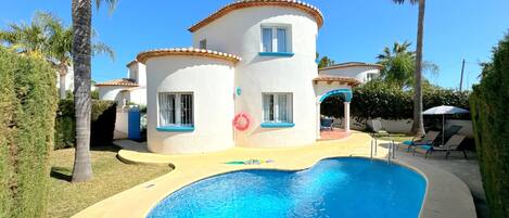 Une maison à deux étages avec une piscine dans le jardin.