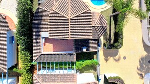 Una piscina en la azotea de forma circular, rodeada por un patio de piedra y abundante vegetación.