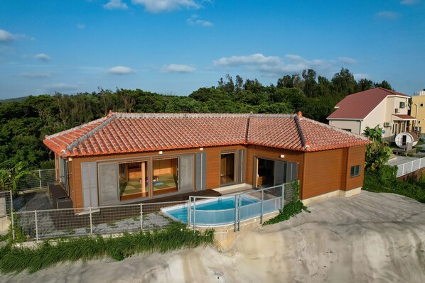 A modern house with a swimming pool, large windows, and a fenced patio area. - Yamagata Ryukyu Hatago Onna Bokairo (Onna)