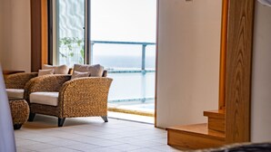 A room with wicker furniture, a view of the sea, and a wooden staircase. - Yamagata Ryukyu Hatago Onna Bokairo (Onna)