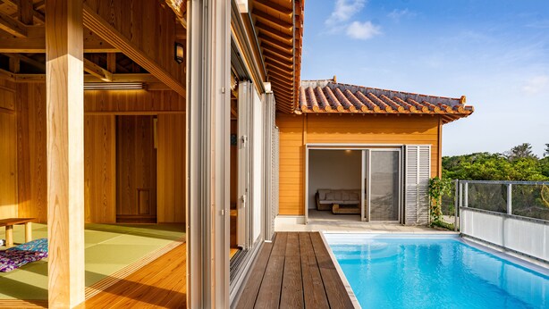 A wooden deck with a pool, sliding glass doors, and a view of a building with a tiled roof. - Yamagata Ryukyu Hatago Onna Bokairo (Onna)