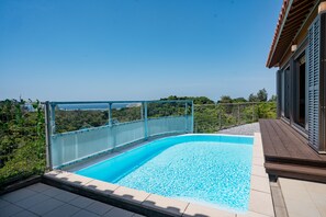 A swimming pool with a glass barrier, surrounded by a wooden deck and a view of a lush landscape. - Yamagata Ryukyu Hatago Onna Bokairo (Onna)