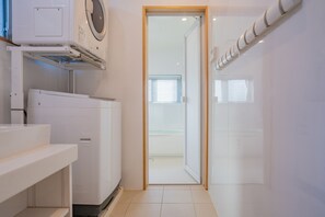 A laundry room with a washing machine, dryer, and a door leading to a bathroom. - Yamagata Ryukyu Hatago Onna Bokairo (Onna)