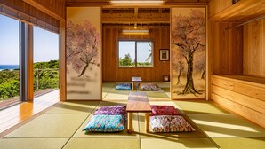 A traditional Japanese room with tatami flooring, a wooden ceiling, and cherry blossom murals. - Yamagata Ryukyu Hatago Onna Bokairo (Onna)