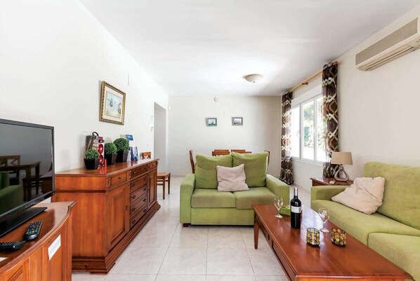A living room with a green sofa, wooden coffee table, and a TV on a wooden cabinet. - 3383 Villa Encina en Moraira (Moraira)