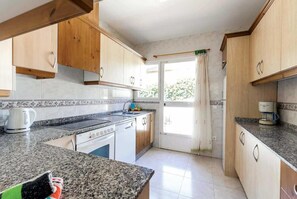 Una cucina con ripiani in granito, mobili in legno, una macchina del caffè e una finestra con tende.