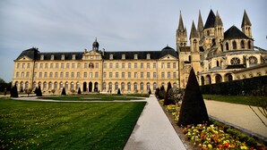 A large, historic building with a symmetrical facade, multiple towers, and a central courtyard with a pathway.