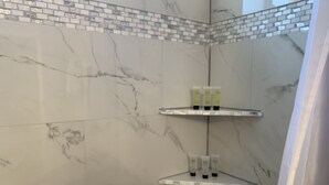 Ein Badezimmer mit Marmorwänden und drei Ablagen für Toilettenartikel.