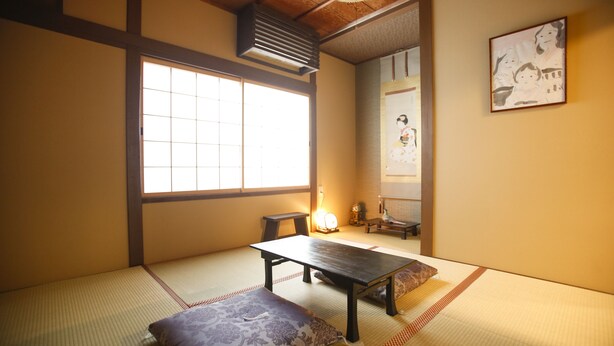 A traditional Japanese room with tatami flooring, a low table, a cushion, and a sliding door. - Yamagata Kyomachi Hatago Kitayamaomiya (Kyoto)