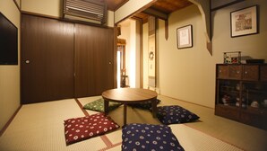 A traditional Japanese room with tatami flooring, a low wooden table, and cushions. - Yamagata Kyomachi Hatago Kitayamaomiya (Kyoto)