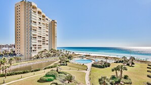 Un hôtel de grande hauteur doté d’une piscine, de palmiers et offrant une vue sur la plage.