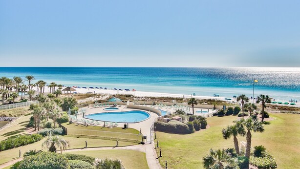Un complexe hôtelier doté d’une grande piscine, d’un accès à la plage et de palmiers.