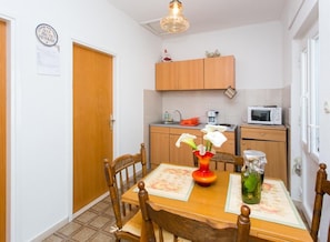 A compact kitchen with wooden cabinets, a microwave, and a small countertop. - Apartments Anka (Dubrovnik)