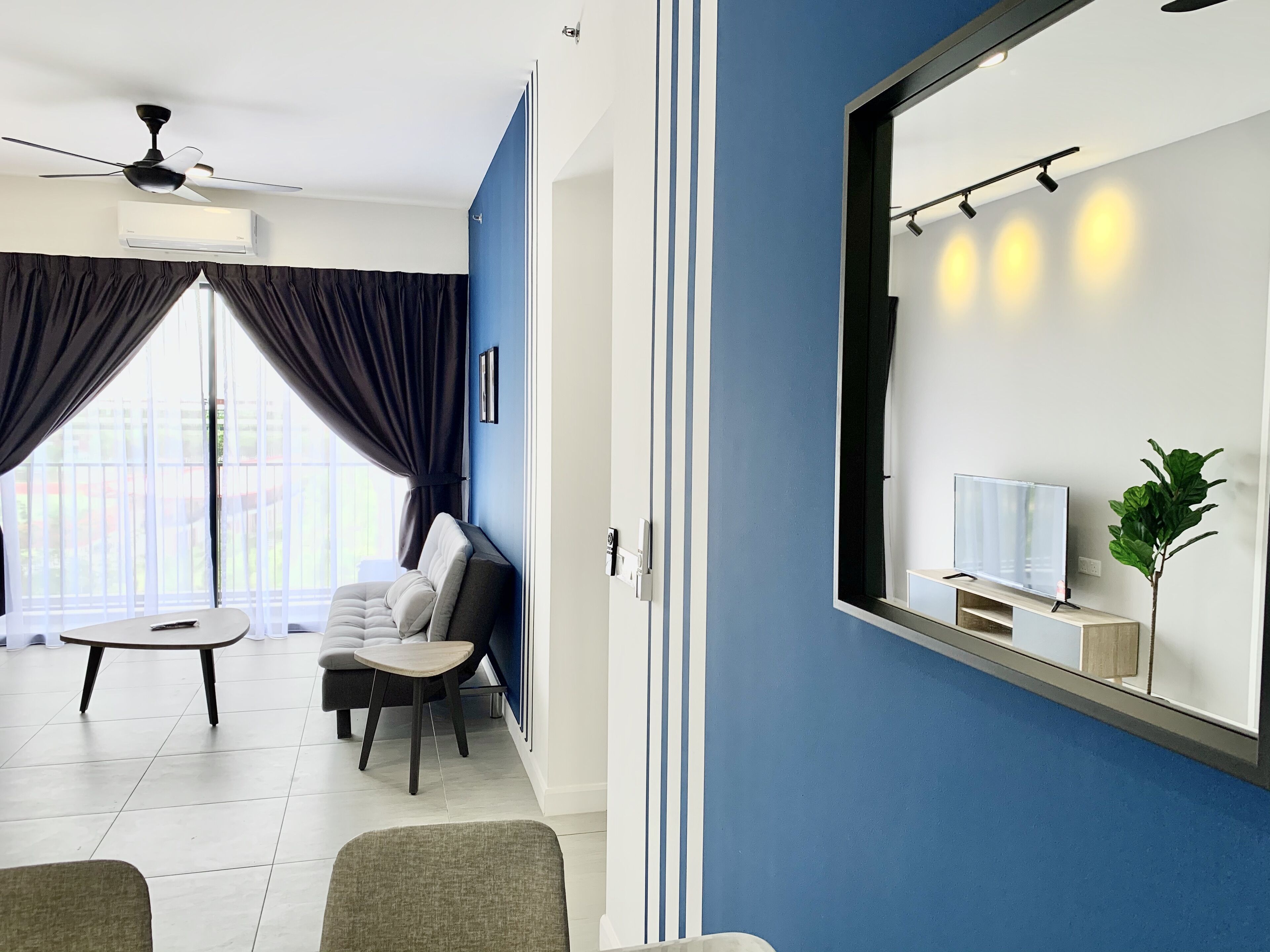 A modern hotel room with a large window, a ceiling fan, a flat-screen TV, and a small plant.