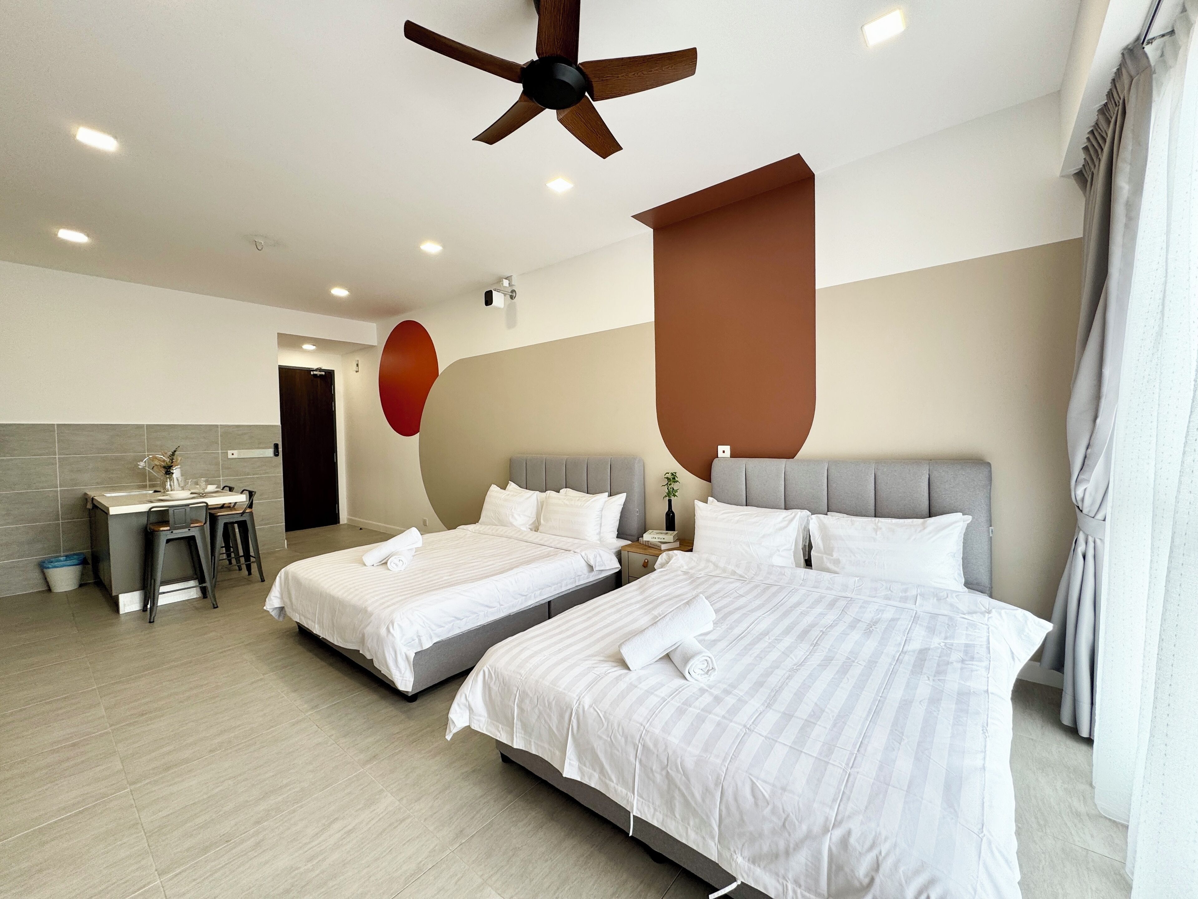 Una habitación de hotel moderna con dos camas, un escritorio y un ventilador de techo.