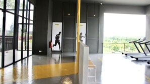 A gym with exercise equipment, large windows, and a view of greenery.