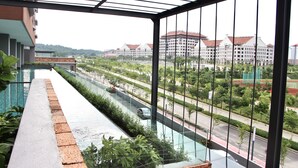 Un balcon donnant sur une route, avec de la verdure et des bâtiments en arrière-plan.
