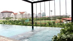 A swimming pool with a view of a sports field and buildings in the background.