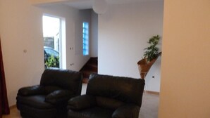Una sala de estar con dos sofás de cuero negro, una mesa de centro de madera y una planta en maceta.