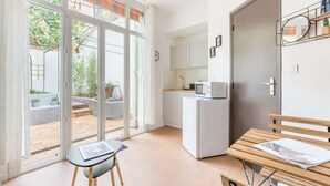 A modern kitchen with a built-in microwave, a refrigerator, and a wooden bench with a magazine. - MaisonMars Studio 3 Blancarde (Marseille)