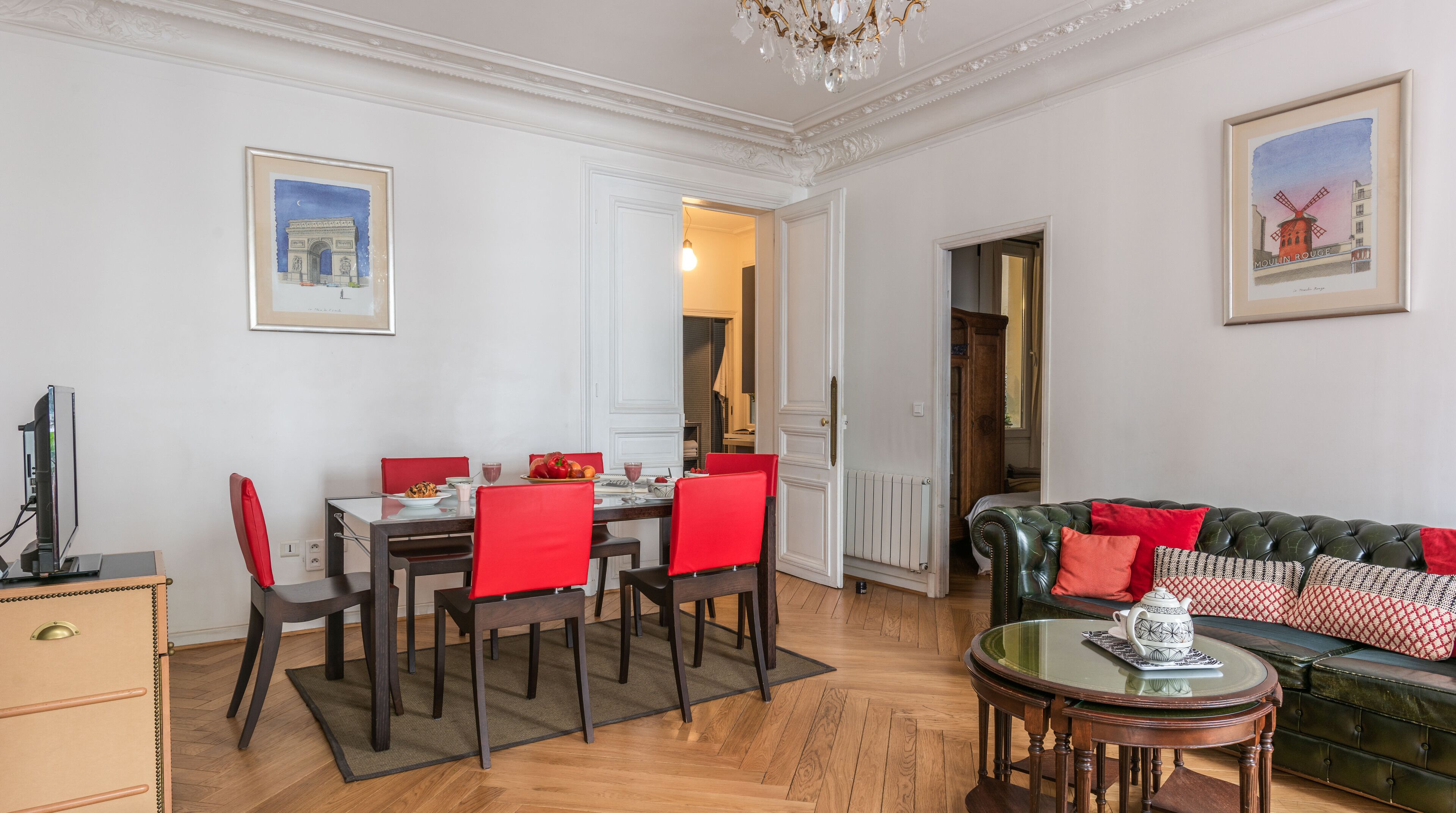 A dining area with a table set for four, red chairs, and a glass-top coffee table.