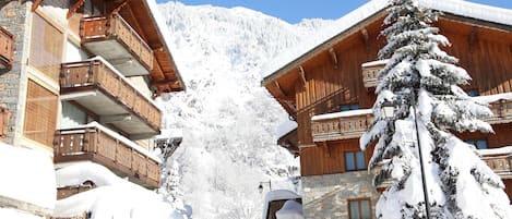 A snow-covered mountain lodge with wooden balconies and a stone facade.