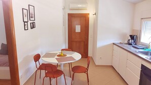 Een compacte keuken met een eethoek, met een ronde tafel met vier stoelen, een koffiezetapparaat en een raam.
