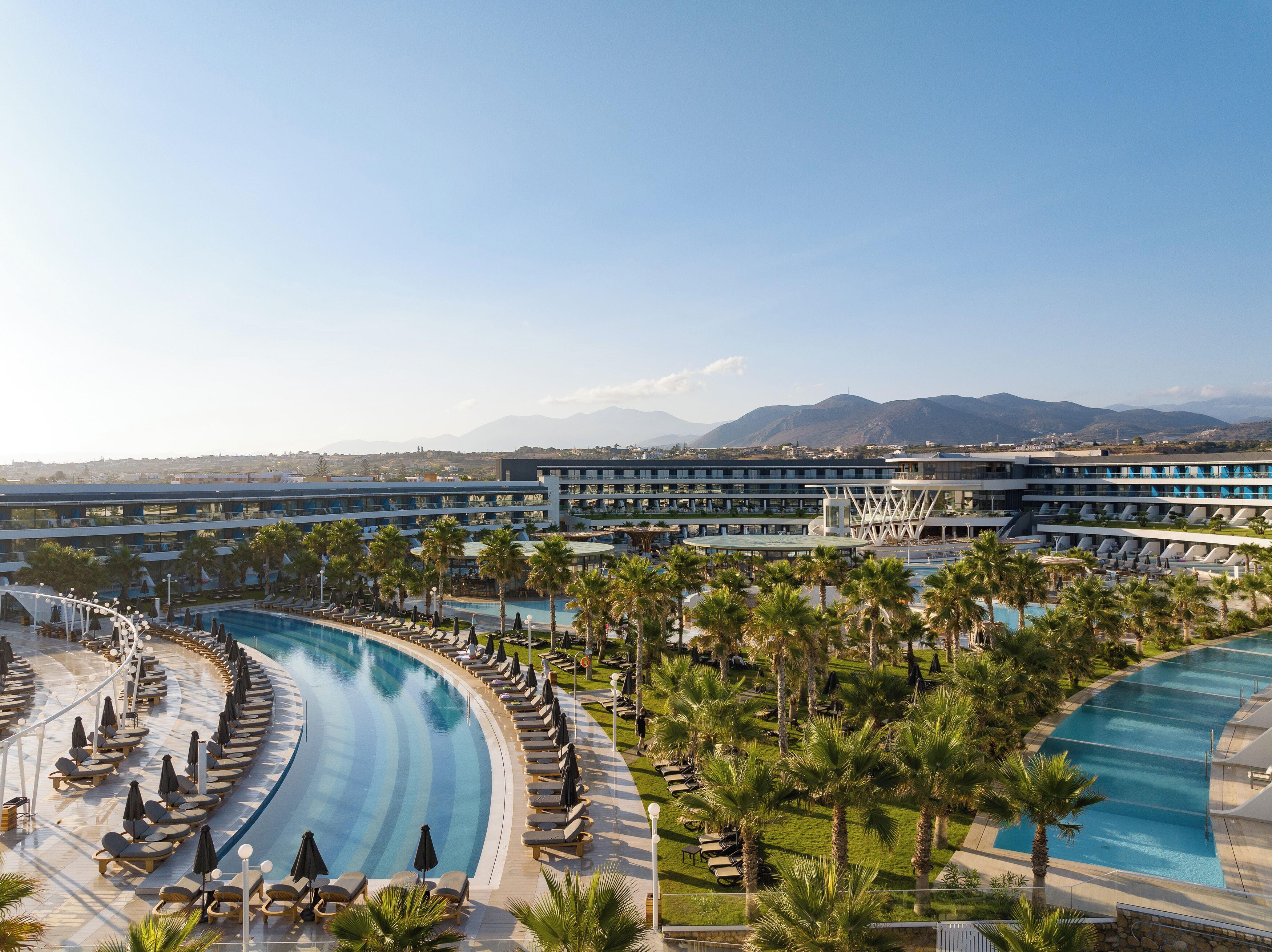 Ein Resort mit großem Pool, Palmen und Bergblick.