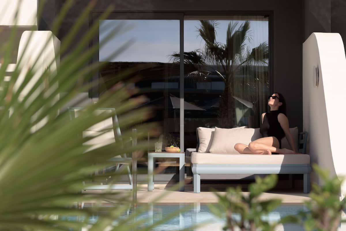 A modern outdoor lounge area with a pool, a sofa, and a table.