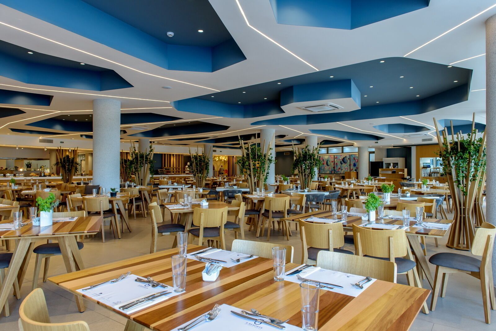 A spacious restaurant with multiple dining areas, wooden tables, and chairs.