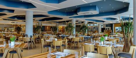 A spacious restaurant with multiple dining areas, wooden tables, and chairs.