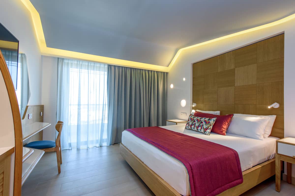 A modern hotel room with a large bed, a desk, and a chair.